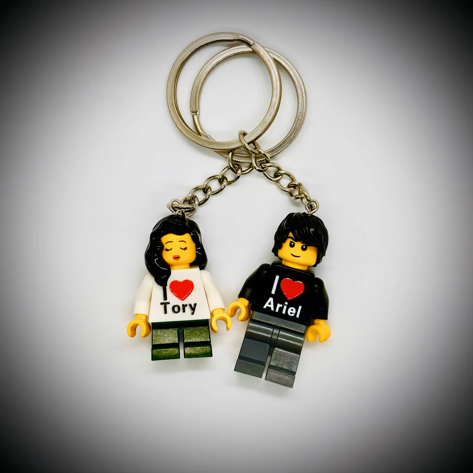 Two custom brick figure keychains with I love Tory and I love Ariel printed on their shirts